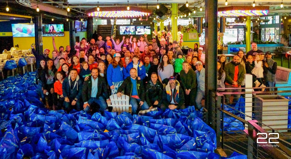 HTX Basket Brigade volunteers gathered behind rows of Thanksgiving food baskets at a past build